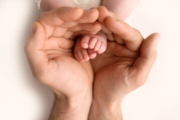 Children's feet in hold hands of father on white. Father and newborn Child. Happy Family people...