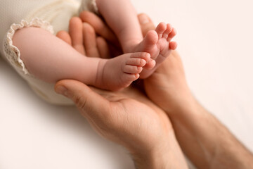 Obraz na płótnie Canvas Children's feet in hold hands of mother on white. Mother and newborn Child. Happy Family people concept.