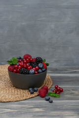 Ripe sweet different berries in bowl on wooden table. Harvest Concept.