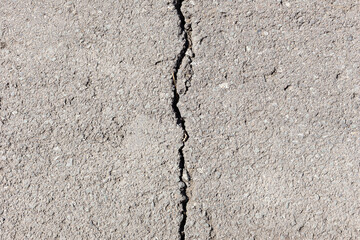 Worn and cracked asphalt with big cracks. Old road concrete texture with cracks
