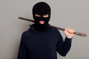Insidious male thief robber looks at camera with smirk, holds iron scrap in his hands, being ready...