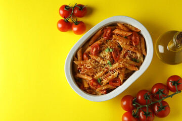 Tray with pasta with tomato sauce and ingredients on yellow background, top view