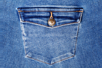 Blue jeans pocket with flap and brass metal button close up, jeans pocket background, blue denim...