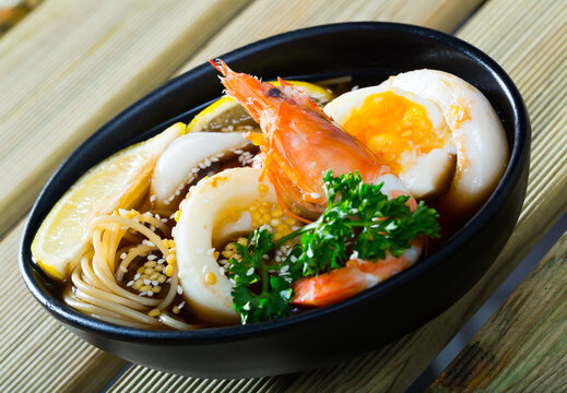 Spicy pan-Asian soup with squid, shrimp, egg noodles and sesame is tasty dish in the kitchen.