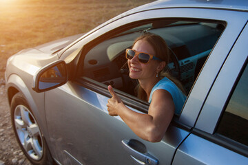 Naklejka premium travel by car. Happy girl with glasses looks out of the car