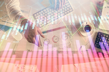 Multi exposure of man's hands typing over computer keyboard and forex graph hologram drawing. Top view. Financial markets concept.