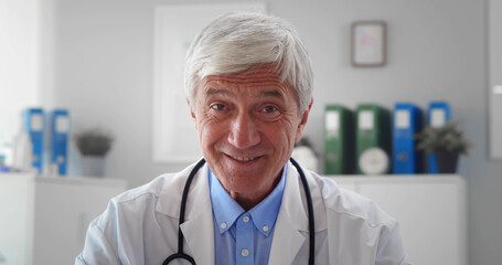 Serious mature doctor wearing white uniform coat with stethoscope speaking looking at camera