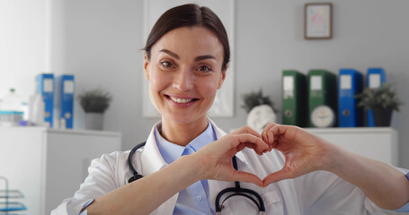 Female doctor showing heart gesture in clinic office