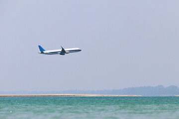 Airplane flies over the sea and sandy beach in mist. Summer vacation and travel concept