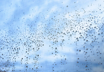 water droplets on a window with a blue and cloudy sky