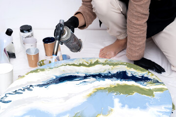 The process of creating a painting using fluid art technique.