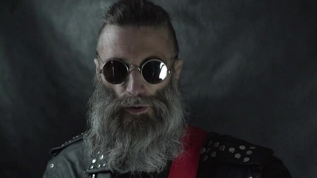 Close up of singing head of bearded rock musician with shaved temples wearing round glasses