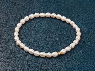 Luxury elegant baroque pearl bracelet on dark blue textured leather background