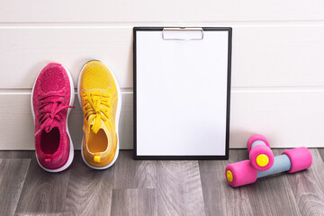 sports at home - pink and yellow sneakers, dumbbells and a note board
