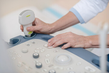 Hands of doctor near control panel and ultrasound sensor