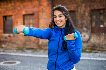 Beautiful woman exercising outdoor with weights outdoor.