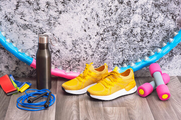 equipment for training at home - yellow sneakers and dumbbells, a jump rope and elastic bands, a hoop and a water bottle for training