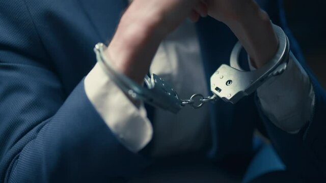 Arrested criminal businessman in handcuffs in the interrogation room. Arrest of the offender. Detention and interrogation of the accused man.