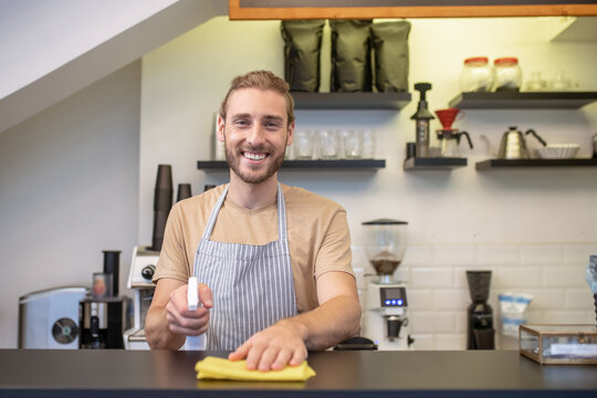 Joyful Young Bearded Man Wiping Bar Counter