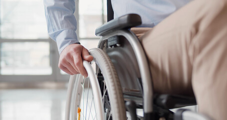 Close up of disabled man riding in wheelchair - obrazy, fototapety, plakaty