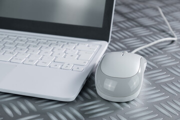 weiße Computer-Maus (mouse) neben einem Notebook / Netbook / Laptop