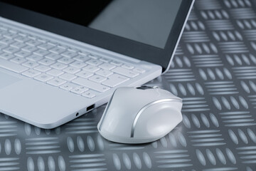 Kabellose Computer-Maus (wireless mouse) neben einem weißen Netbook / Notebook / Laptop