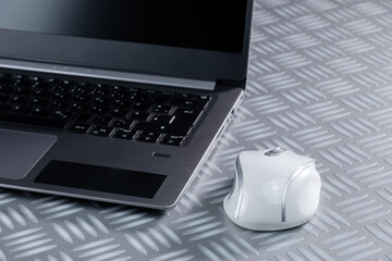 Kabellose Computer-Maus (wireless mouse) neben einem Aluminium-Notebook / Laptop, weiße Maus auf...