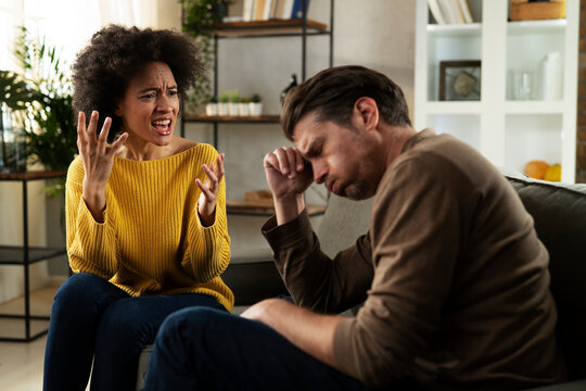 Frustrated young couple arguing at home. Stressed unhappy wife and husband sitting on cauch at home