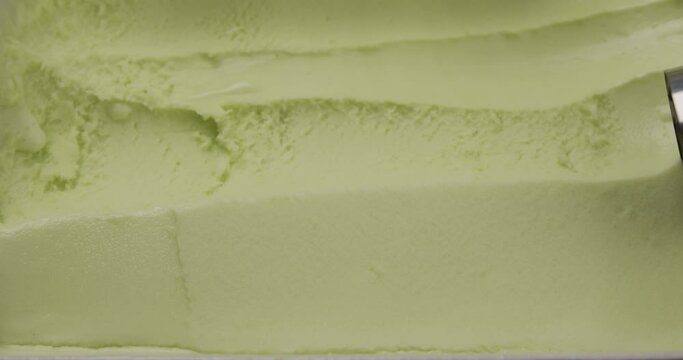 Slow motion Close up Stainless steel ice cream scoop is scooping Green tea flavor ice cream meat.
