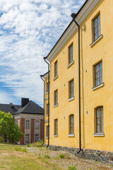 A yellow building in a European city illuminated by the sun against the background of another red building and a blue sky .