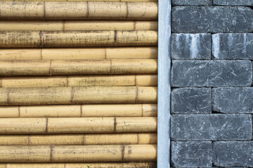 Mauer aus dicken Bambusrohren und schwarzen Steinen
