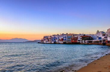 Beautiful sunset view of Little Venice, Mykonos, Greece. Romantic neighborhood with bars, cafes, restaurants in old fisherman houses above sea waves