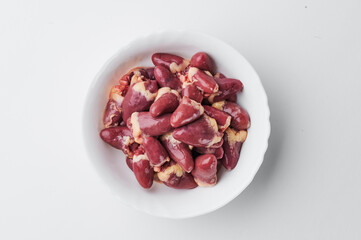 raw chicken hearts in a white plate on a white background. Close-up. 