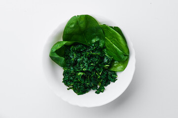 spinach (fresh and freeze spinach) blanch. on a white plate on a light background. Top view. Mockup