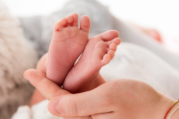 Italy, April 2021. Mom holds the feet of her newborn baby in her hand