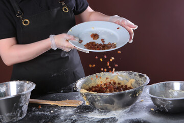 Raisins are added to the dough. The pastry chef kneads a thick dough for cakes.Baking cakes for the Easter holiday.Thick dough for festive baking. An unrecognizable person.