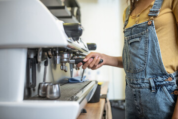 Female hand holding lever of coffee machine