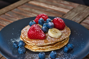homemade pancakes topped with banana strawberries and blueberries 