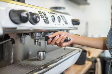 Womans hand holding holder of coffee machine