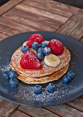 homemade pancakes topped with banana strawberries and blueberries 