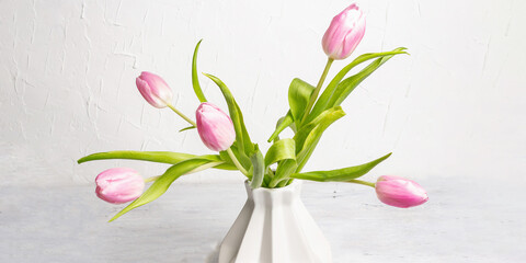 Bouquet of gentle pink tulips in ceramic vase on white background