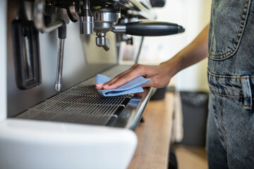 Womans hand washing surface of coffee machine