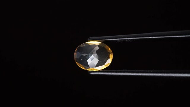 natural yellow fire opal gemstone in the tweezer on the background