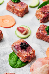Composition with raw square cutlets on light background. Natural food for dogs. BARF dog diet. Close up