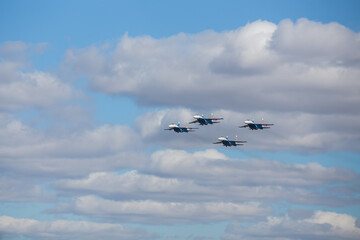 four jet planes are flying in a tight formation. dangerous aerobatics are shown at the aviation festival by pilots. military parade of modern fighter planes