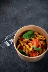 Casarecce pasta with tomato and basil in a taking away box. food delivery from the restaurant to your home.