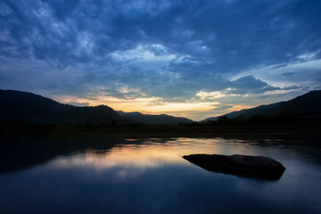  scenery silhouette Mountains The sky cools after the sun goes down, the rain clouds are moving, reflecting the water in the river, there are rocks in the water, giving a feeling of loneliness.