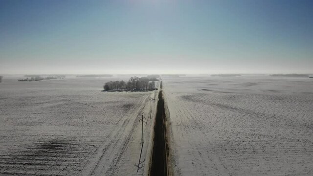 Rising aerial drone shot of empty dirt road in winter with snow