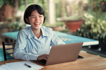 smiling asian woman with working on laptop in coffee shop cafe