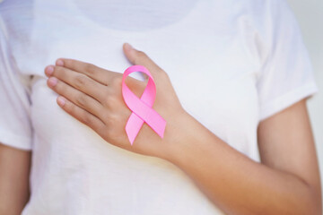 woman hand holding pink ribbon on chest.healthcare and medicine concept. breast cancer awareness